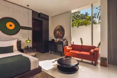 a bedroom with a bed and a couch and a chair at Chaesa Comfortable 1 BR Royal Private Pool Villa in Kerobokan