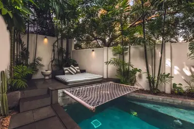 a backyard with a pool and a bench next to a fence at Chaesa Comfortable 1 BR Royal Private Pool Villa in Kerobokan