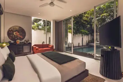 a bedroom with a bed and a tv and a pool at Chaesa Comfortable 1 BR Royal Private Pool Villa in Kerobokan