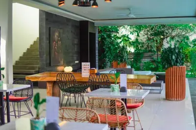 an empty restaurant with tables and chairs and stairs at Varenya Cozy 1 BR Suite Twin Room in Kerobokan