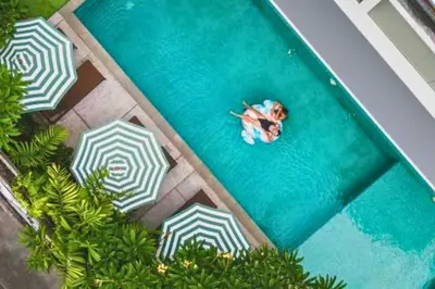 an overhead view of a person swimming in a pool with umbrellas at Varenya Cozy 1 BR Suite Twin Room in Kerobokan