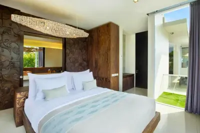 a bedroom with a large white bed and a chandelier at Varnika Peaceful 1 BR Suite Double Room in Kerobokan