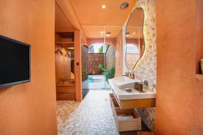 a bathroom with a sink and a tv on a wall at Yaseera Aesthetic 1 BR Grand Smart Private Pool Villa in Seminyak