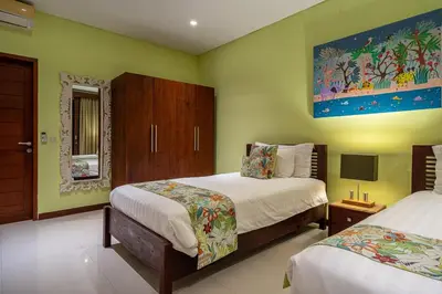 a bedroom with two beds and a painting on the wall at Villa Rajawali 3BR Private Villa Near Beach in Canggu