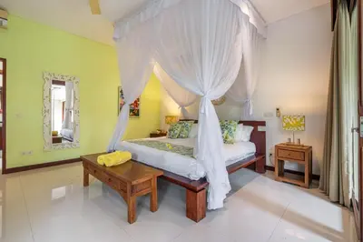 a bedroom with a canopy bed and a table at Villa Rajawali 3BR Private Villa Near Beach in Canggu