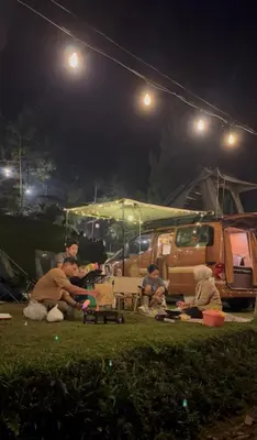 a group of people sitting in the grass at night at Wandervan - Bali Campervan Rental in Kuta