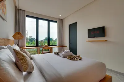 a bedroom with a white bed with a tv on the wall at Elegant Villa Vibhava 2BR in Central Umalas in Kerobokan