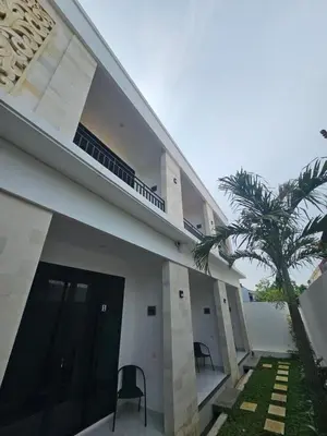 a building with two chairs and a palm tree at Kubu Semangka in Sanur