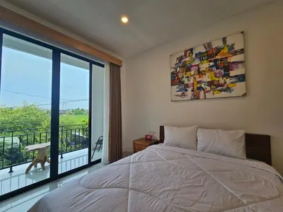a bedroom with a bed and a large window at Kubu Semangka in Sanur