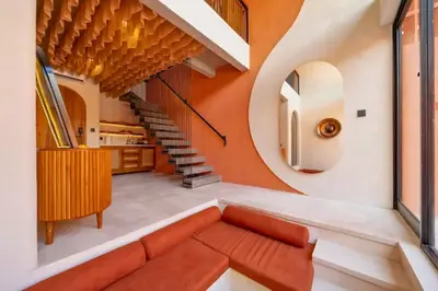an orange and white living room with a couch and stairs at Tamasvini Romantic 1 BR Grand Private Pool Villa With Bathtub in Seminyak