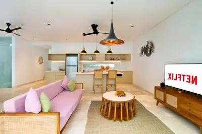 a living room with a pink couch and a kitchen at Heleina Elegant 3 BR Royal Private Pool Villa With Jacuzzi in Legian