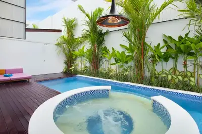 a hot tub on a deck next to a building with trees at Heleina Elegant 3 BR Royal Private Pool Villa With Jacuzzi in Legian