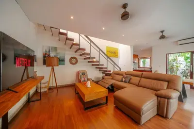 a living room with a couch and a staircase at Stunning villa in Umalas center in Canggu