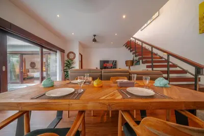 a dining room with a wooden table and a couch at Stunning villa in Umalas center in Canggu