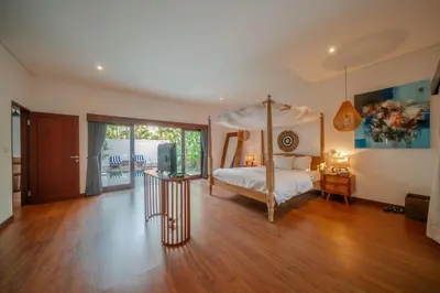 a bedroom with a canopy bed and a wooden floor at Stunning villa in Umalas center in Canggu