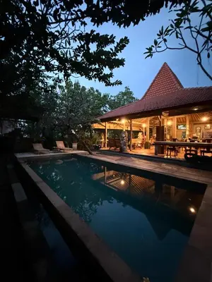 a swimming pool in front of a house at night at Kundalini Shakta Yoga Meditasi in Denpasar
