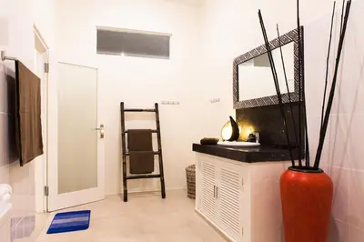 a bathroom with a red vase and a mirror at Cozy 2br villa at the beach in Canggu