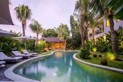 a swimming pool in front of a house with palm trees at Anam Mani New Room Central Seminyak in Seminyak