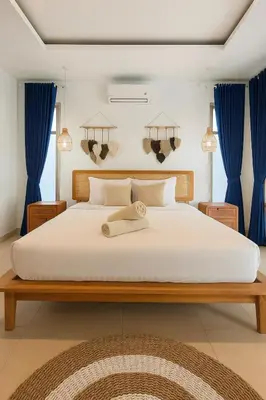 a bedroom with a large white bed with blue curtains at Blush Elegance 2 BR Villa in Umalas in Canggu