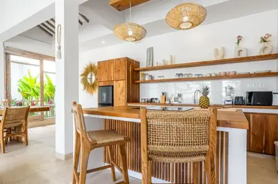 a kitchen with wooden cabinets and a bar with chairs at Blush Elegance 2 BR Villa in Umalas in Canggu