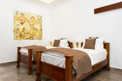 two beds in a room with a painting on the wall at Beachside Luxury Private Villa in Sanur in Sanur
