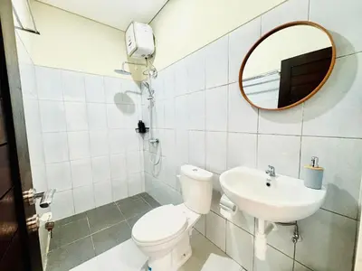 a bathroom with a toilet and a sink and a mirror at Umah Anami in Denpasar