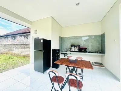 a kitchen with a table and chairs and a refrigerator at Umah Anami in Denpasar