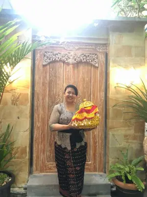 a woman holding a cake in front of a door at Pujihouse One in Legian