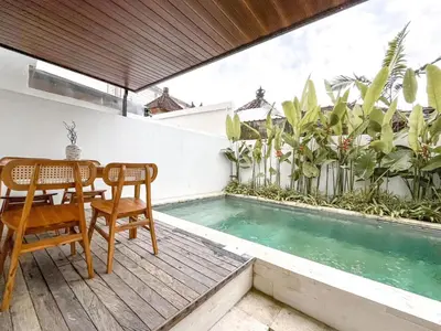 a patio with a table and chairs next to a swimming pool at Villa Morich in Jimbaran