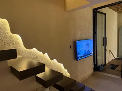 a living room with stairs and a tv on the wall at LoftStyle Villa with nice Private Plunge Pool in Kerobokan