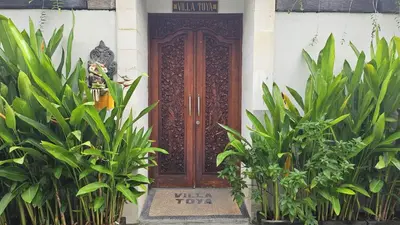 a wooden door on a house with plants in front at Villa Toya in Legian