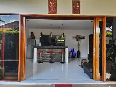 a living room with a kitchen with red stools at Villa Toya in Legian