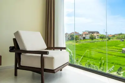 a chair sitting in front of a large window at Casa Alden - 3BR Infinity Pool with Ricefield View in Kerobokan