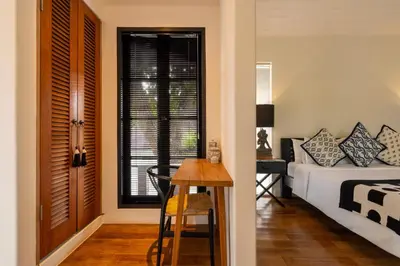 a bedroom with a bed and a table and a window at Walk into Serenity, Martini 3 - 1BR Treetop Villa in Kerobokan