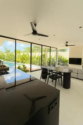 a living room with a table and chairs and windows at Villa Kina - Tropical 2BR Villa with Pool and Billiard in Seminyak