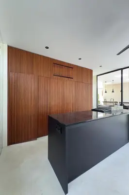 a kitchen with a black counter and wooden wall at Villa Kina - Tropical 2BR Villa with Pool and Billiard in Seminyak