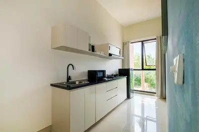 a kitchen with white cabinets and a sink and a window at Amelia D Art Deco Suites in Seminyak
