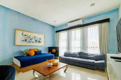 a blue bedroom with a bed and a couch at Amelia D Art Deco Suites in Seminyak