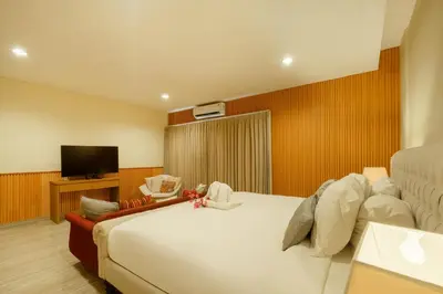 a bedroom with a large bed and a flat screen tv at Amelia D Art Deco Suites in Seminyak