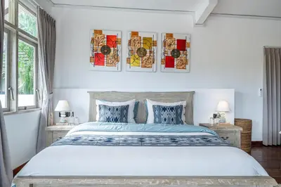 a white bedroom with a large bed with blue sheets at Villa Arisanti in Kerobokan