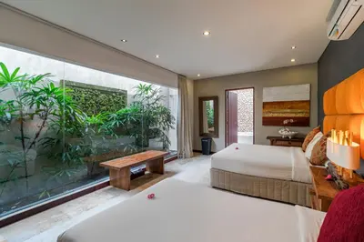 a bedroom with two beds and a large window at Joglo-Style 3 Bedroom Villa in Heart Of Seminyak in Seminyak