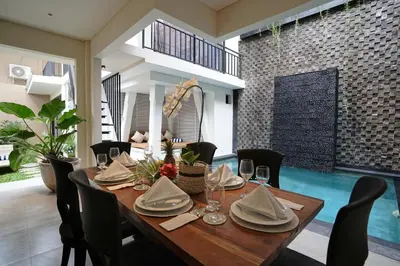 a dining room with a wooden table and chairs at Cleo Villa Padma Legian in Seminyak