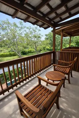 two wooden benches sitting on a porch with a table at Royal Tulip Springhill Resort Villa Kunyit 12 in Jimbaran