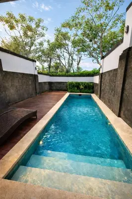 a swimming pool in a backyard with a wooden deck at Royal Tulip Springhill Resort Villa Kunyit 12 in Jimbaran