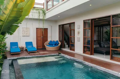 a villa with a swimming pool and two blue chairs at Villa Aurikari in Legian