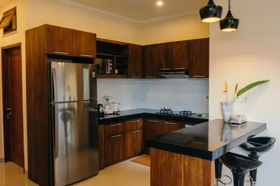 a kitchen with wooden cabinets and a stainless steel refrigerator at Villa Aurikari in Legian