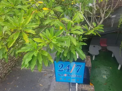a sign in front of some plants and a couch at 24/7 Bed & Breakfast in Jimbaran