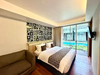 a bedroom with a bed and a couch and a window at Dealton Hotel Sanur in Sanur