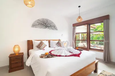 a bedroom with a bed with white sheets and a window at Villa WENDY Mertanadi in Seminyak