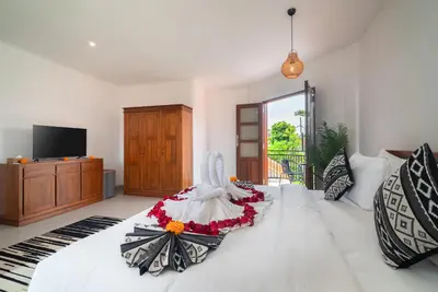 a bedroom with a large white bed with flowers on it at Villa WENDY Mertanadi in Seminyak
